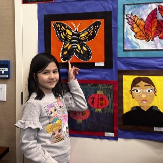 student pointing to her artwork