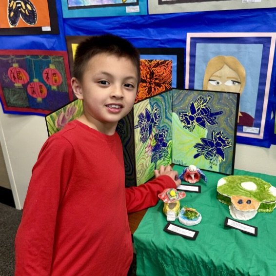 student pointing to his artwork