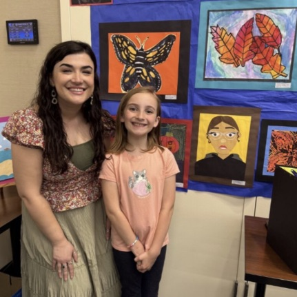 student and Ms. Cummings standing by art project 
