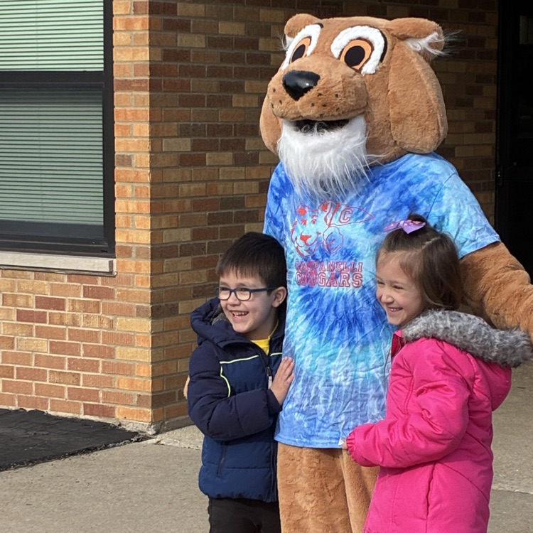two students standing with Cody, our mascot 
