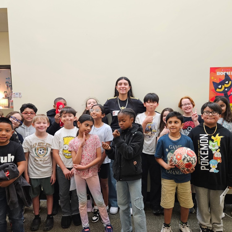 Third graders posing for a group photo with a professional soccer player