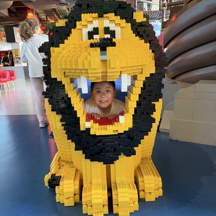 Fourth grader posing inside a LEGO lion