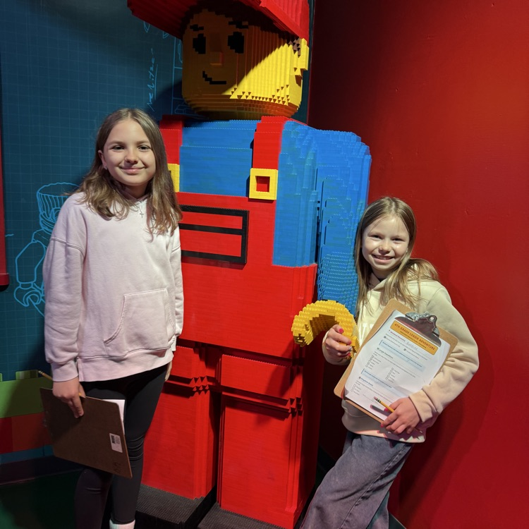 Fourth graders posing with a LEGO statue