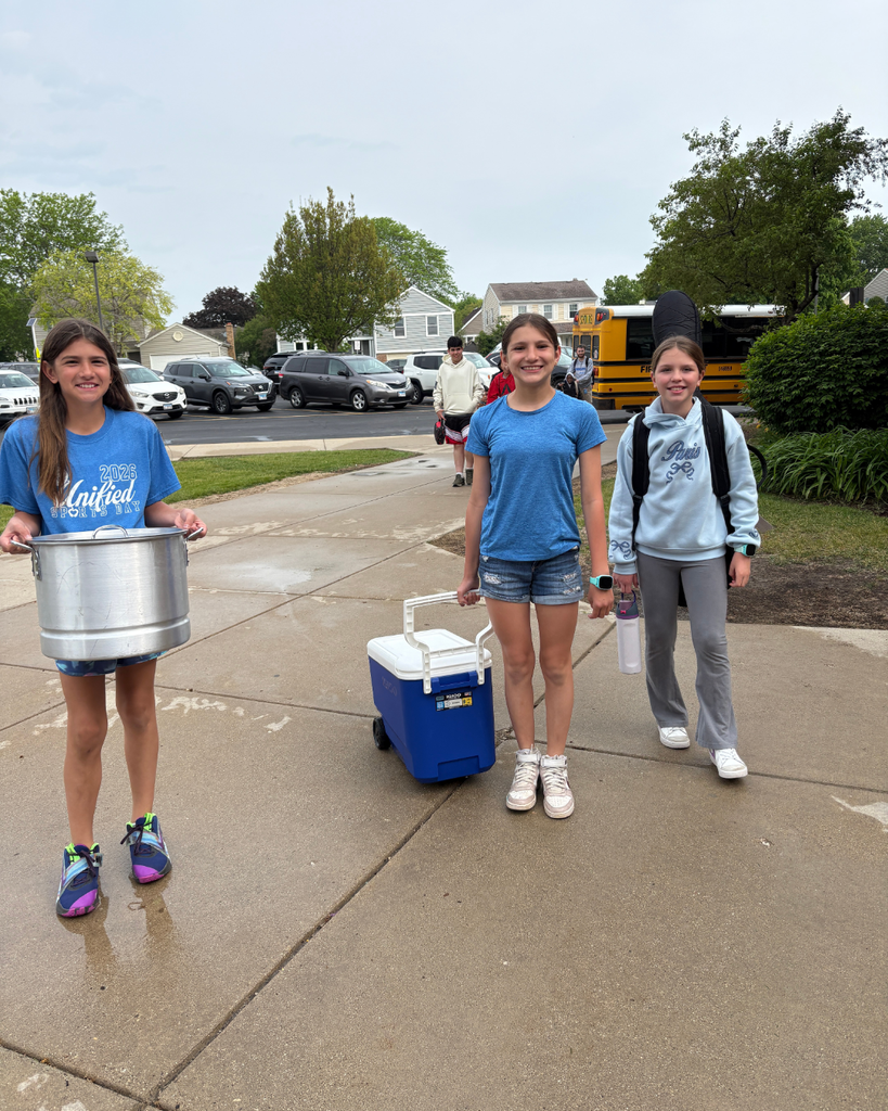 Student carrying a pot, student pulling a cooler, and student using a guitar case as a backpack
