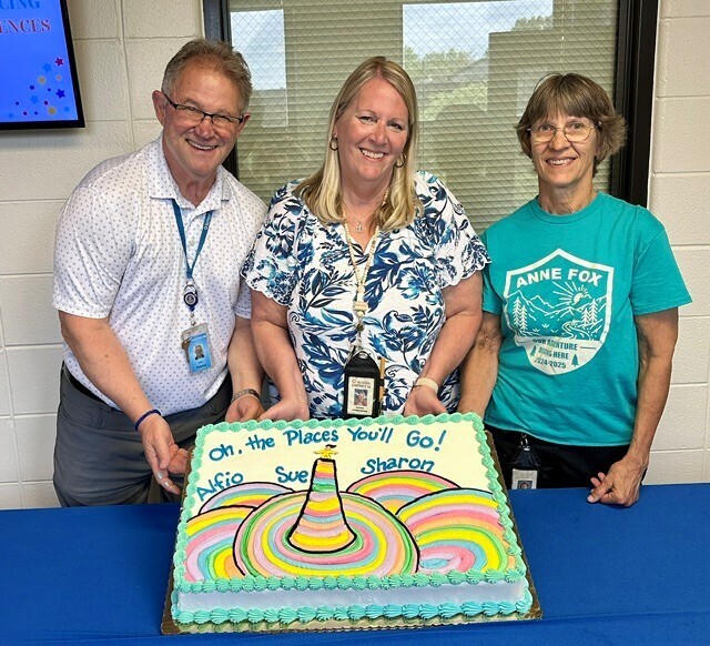 Three teacher retirees posing with a congratulatory cake