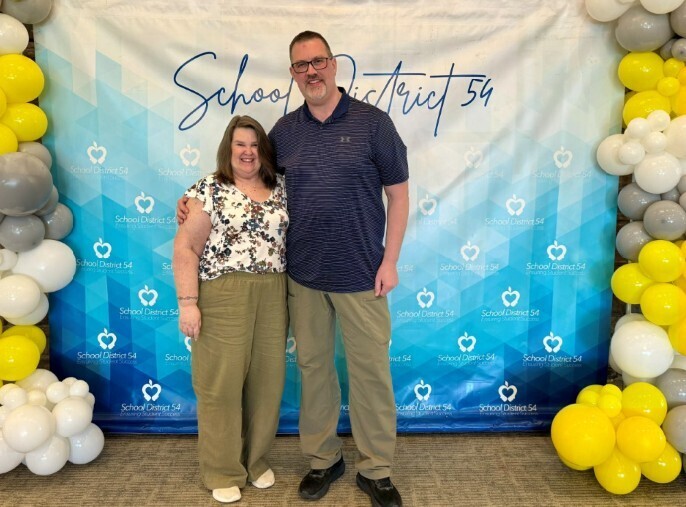 Cathy Duke and Todd Doerpinghaus pose in front of backdrop