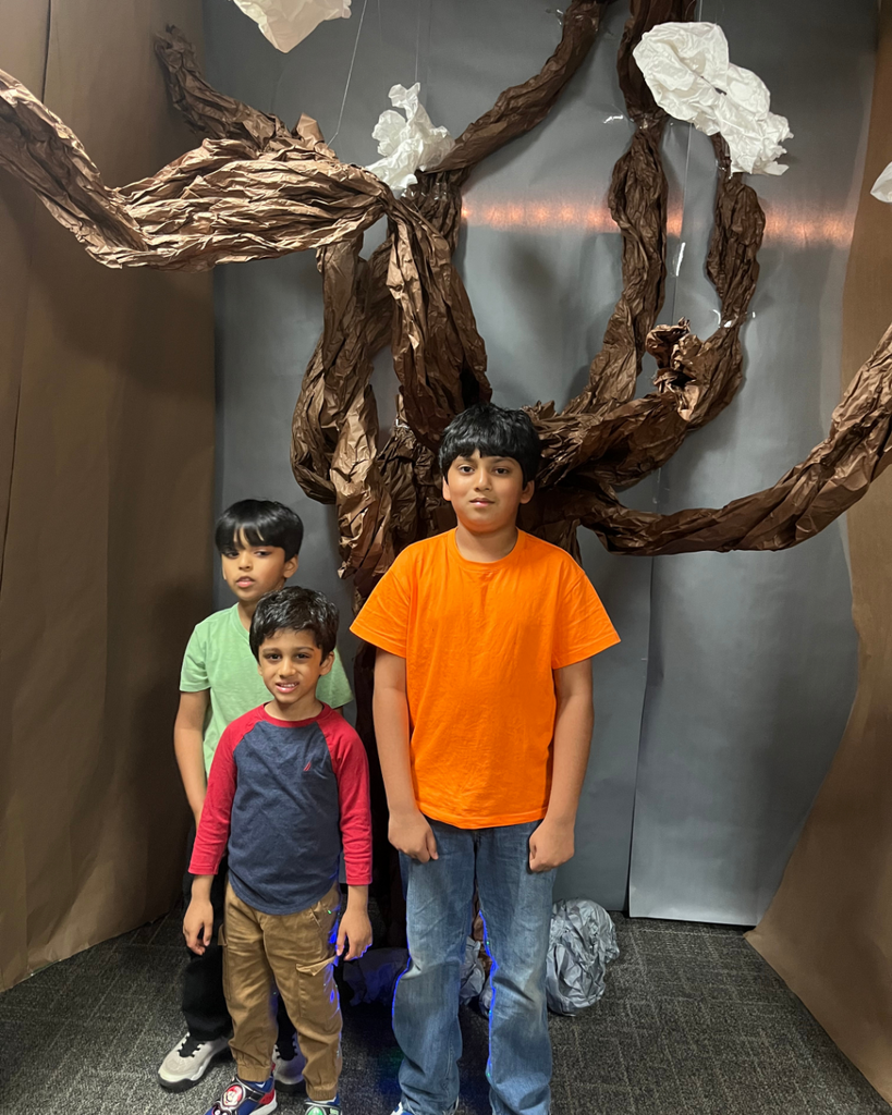 Family of students posing in front of a tree artwork structure