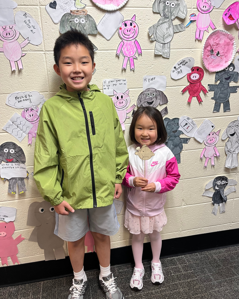 Students smiling with Elephant and Piggie artwork
