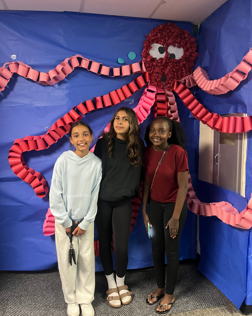 Students posing and smiling in front of their octopus artwork structure