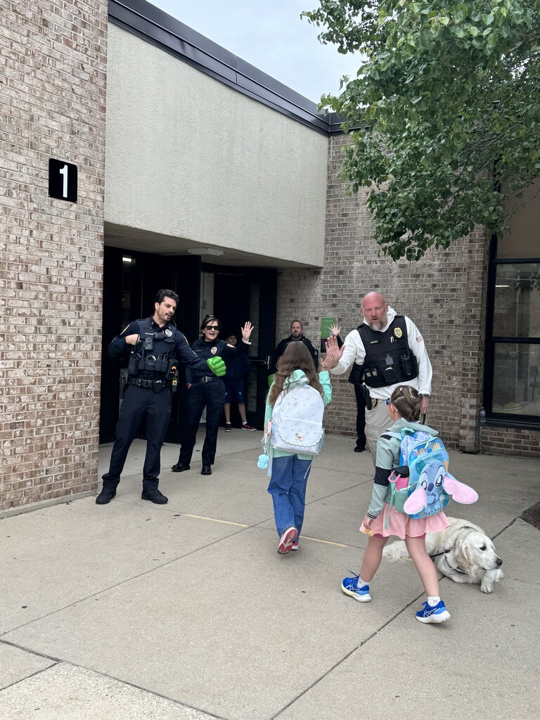 Police officers and their therapy dog greeting students as they come into school.