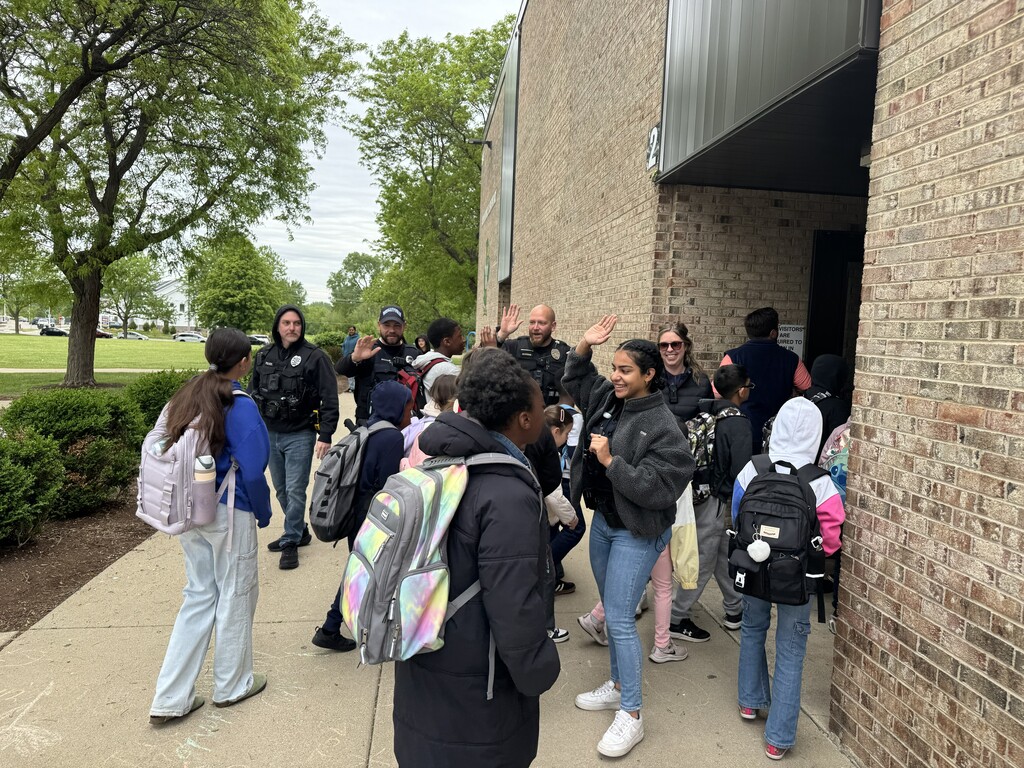 Police officers greeting students with high-fives on the way into school.