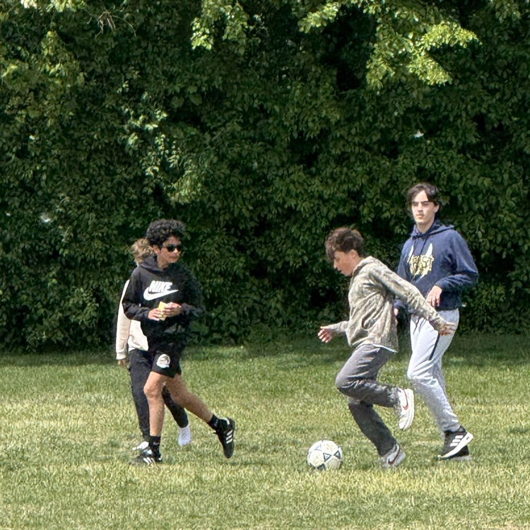 teens playing soccer on grass 