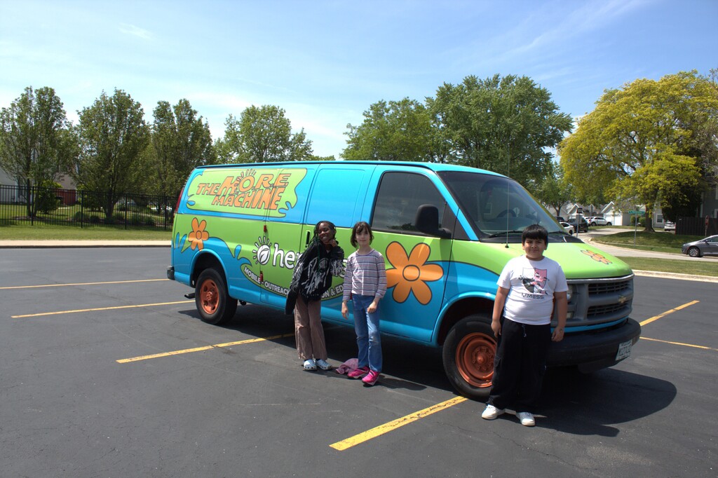 Students standing by the Mystery Machine