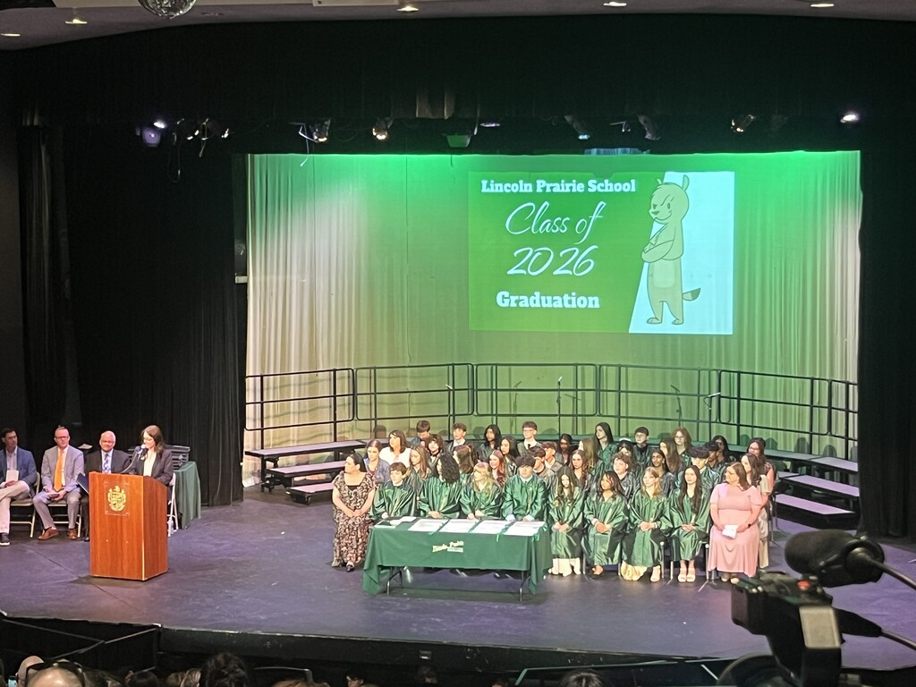 8th grade graduates listening to their principal give a speech.