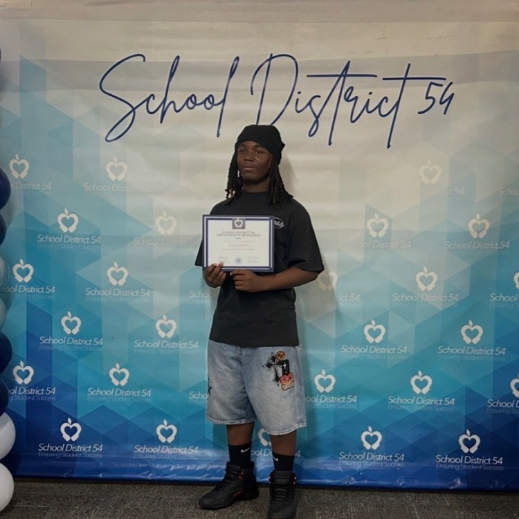 A Keller Wildcat student standing in front of a backdrop being recognized for an athletic award. 