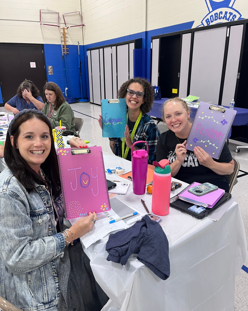 Teachers smiling with clipboards they decorated