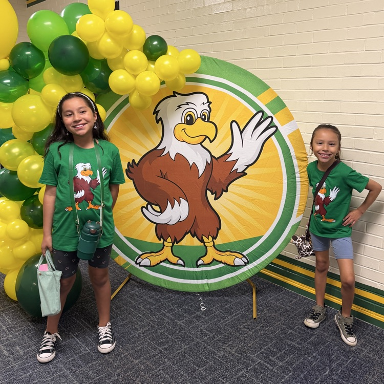 Sisters smiling in front of the balloon arch.