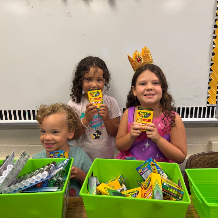Two students and a younger brother sorting supplies.