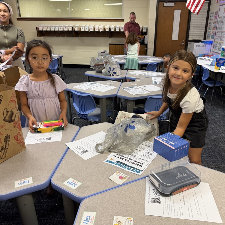 Two students putting supplies in their desks.