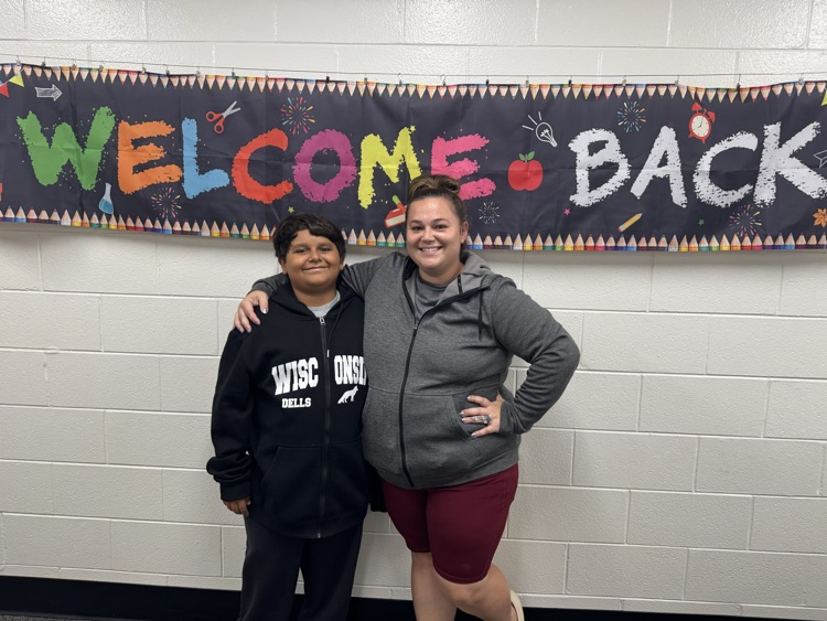 mom and son smiling in front of a back to school sign