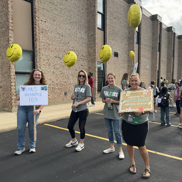 teachers waiting for their students holding balloons and signs