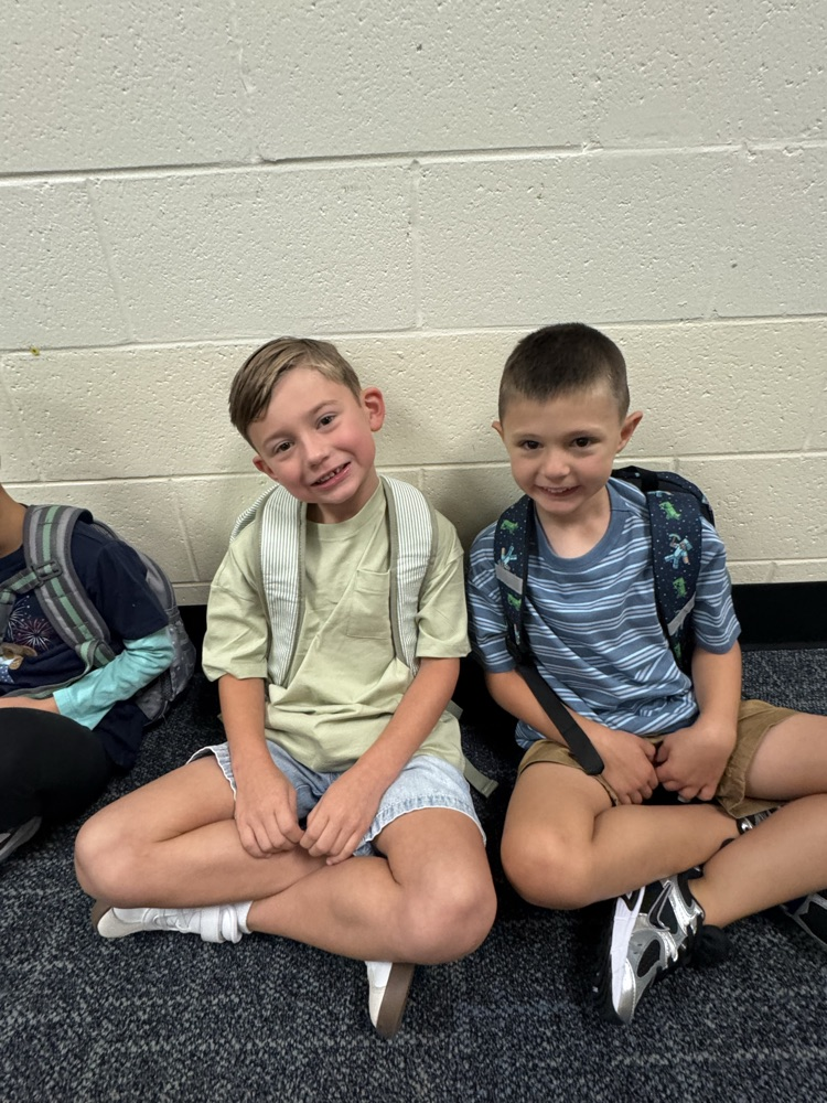 2 friends sitting next to each other before school starts.
