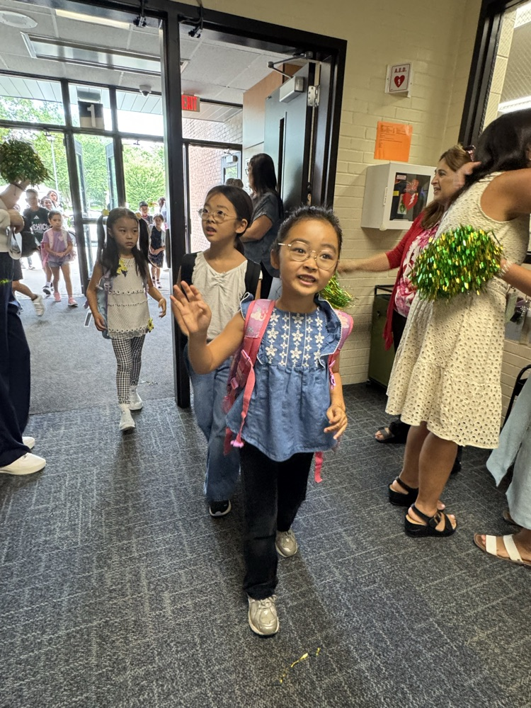 Student walking in with teachers cheering on the first day of school.