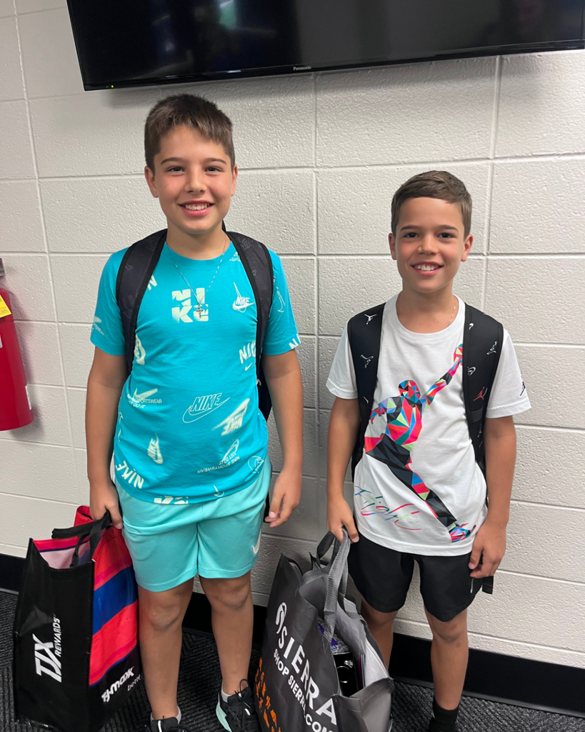 2 brothers smiling together with backpacks on before their first day