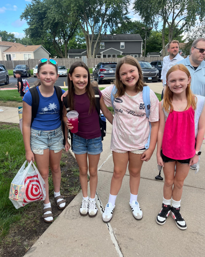 4 student girls smiling together outside with backpacks on before their first day