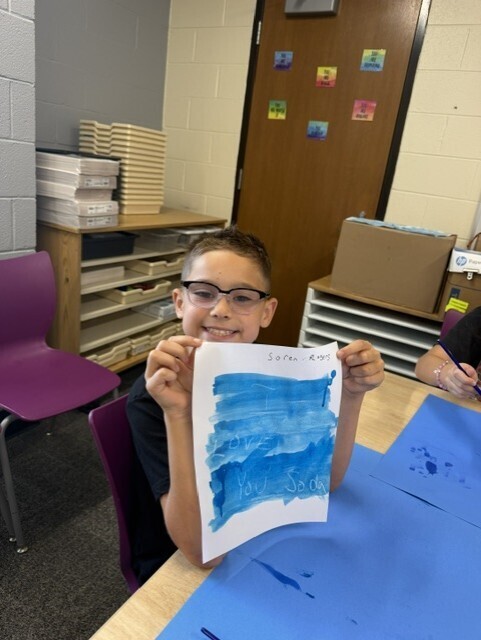 Student holding up a secret message revealed with water color paints
