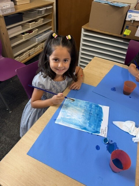 Student holding up a secret message revealed with water color paints