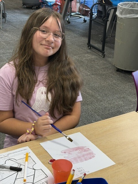 Student revealing a secrect message with water color paints