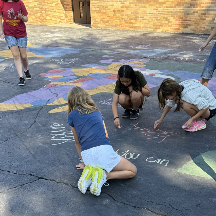 students creating positive message with chalk