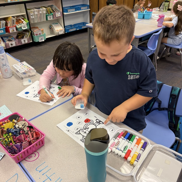 two students coloring in a paper
