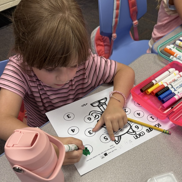a student coloring in a number on a paper.
