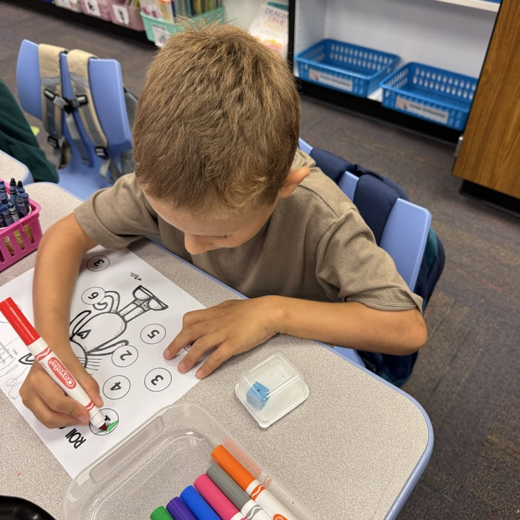 a student coloring a number on a paper