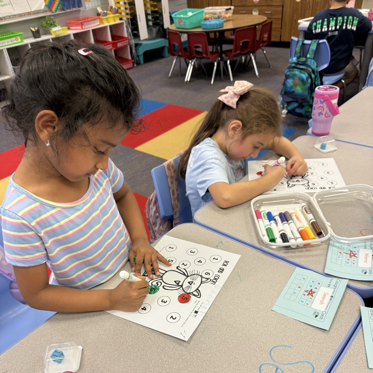 two girls coloring in a paper
