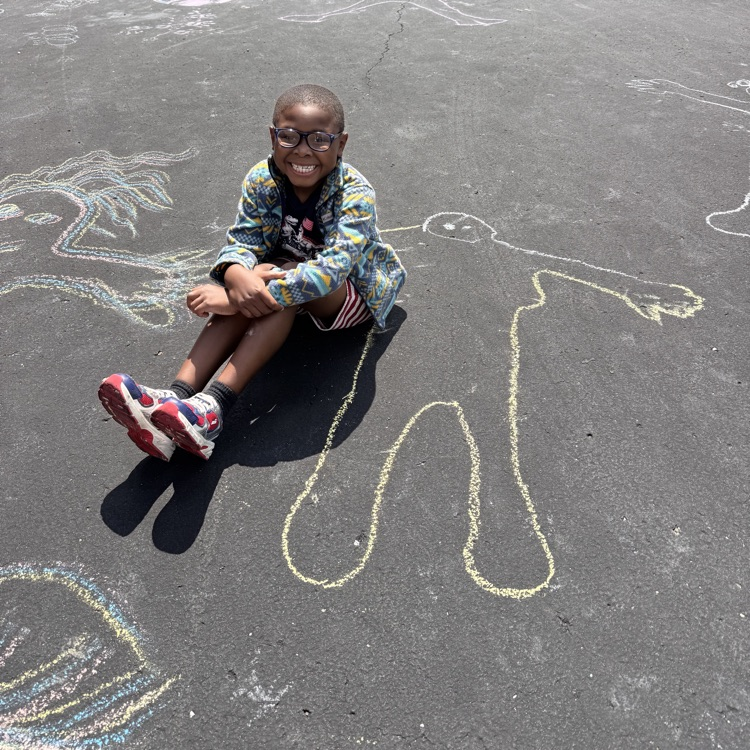 Student next to chalk person drawn on blacktop