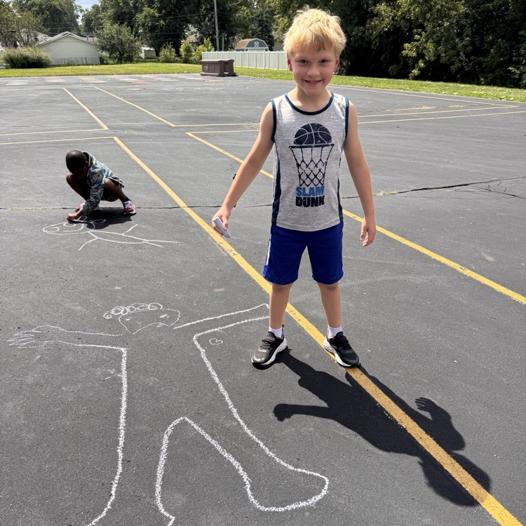 Student next to chalk person drawn on blacktop