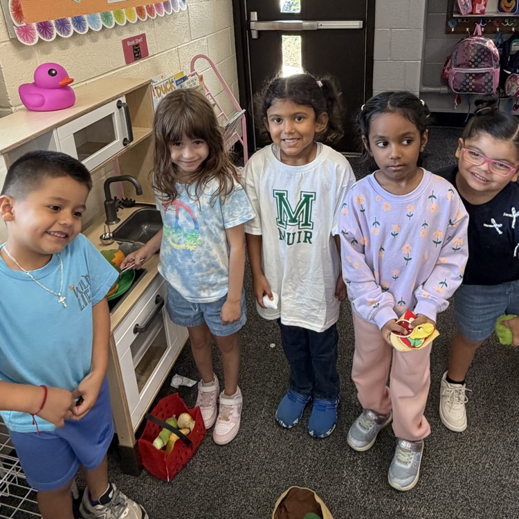 students standing by a play kitchen
