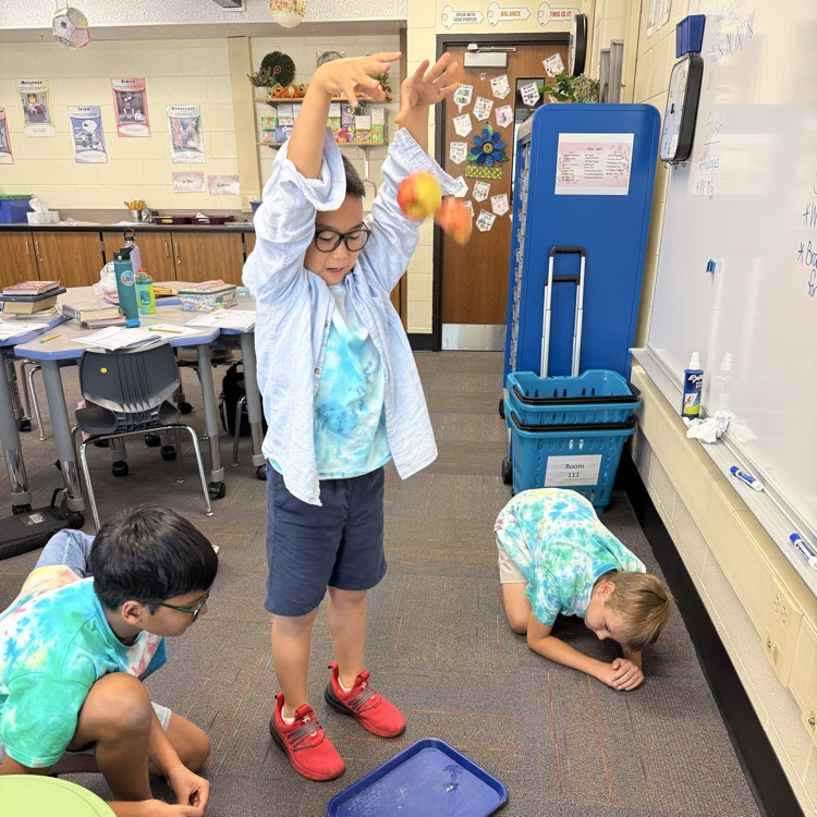 three students getting ready to drop an apple