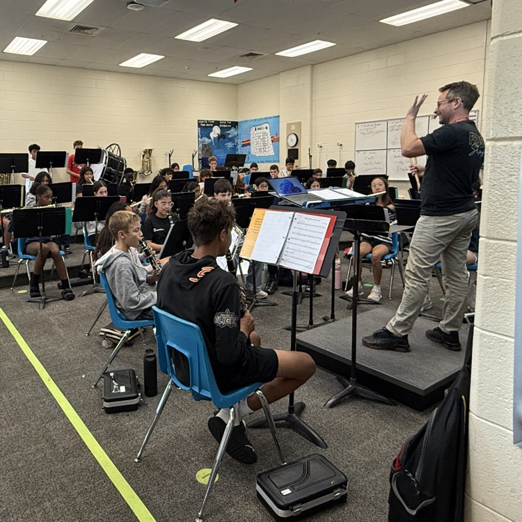 band director standing on podium students playing instruments