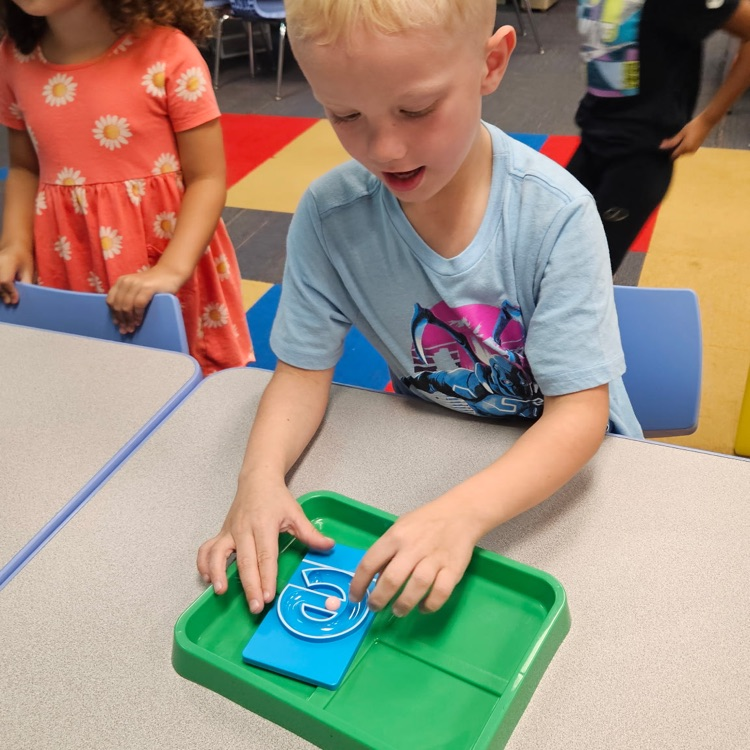 student creating the letter e with marbles 
