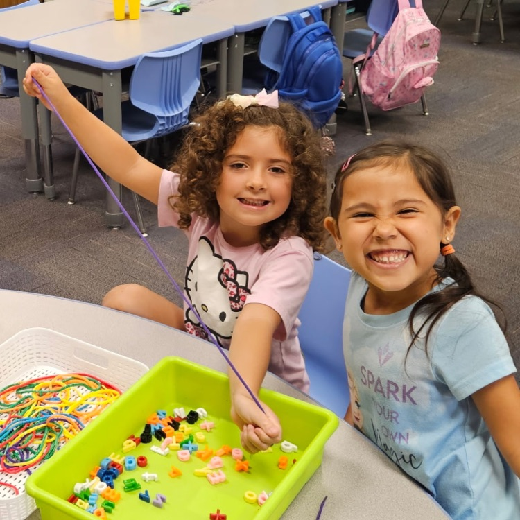 two girls stringing letter beads 