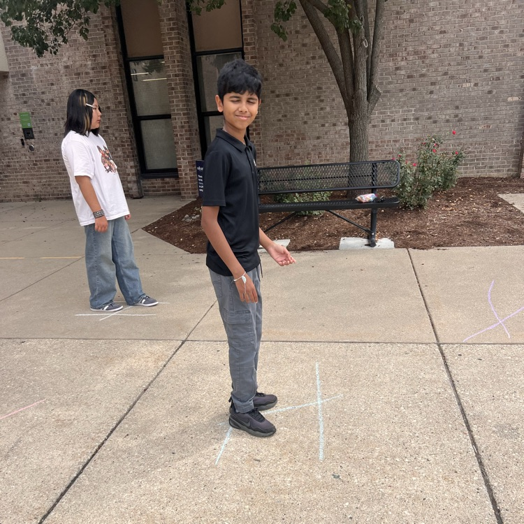 student standing on chalk lines drawn on sidewalk