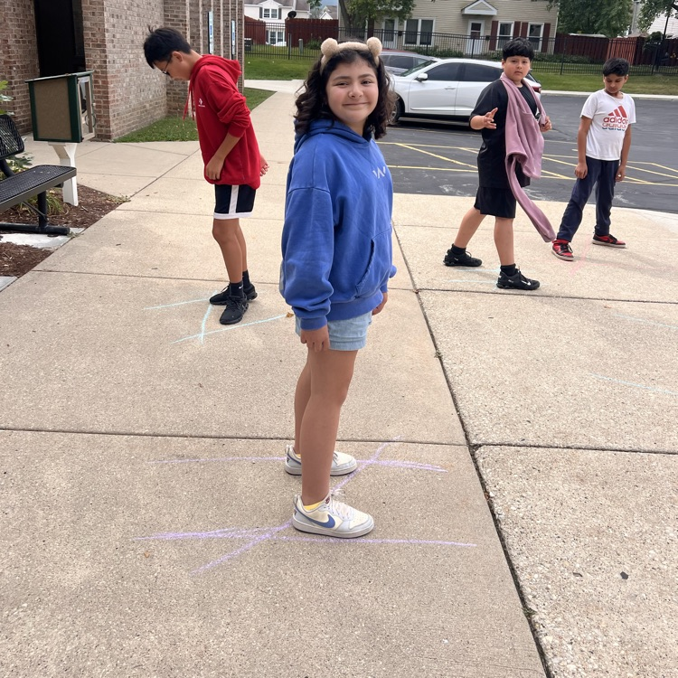 students standing on chalk lines on sidewalk