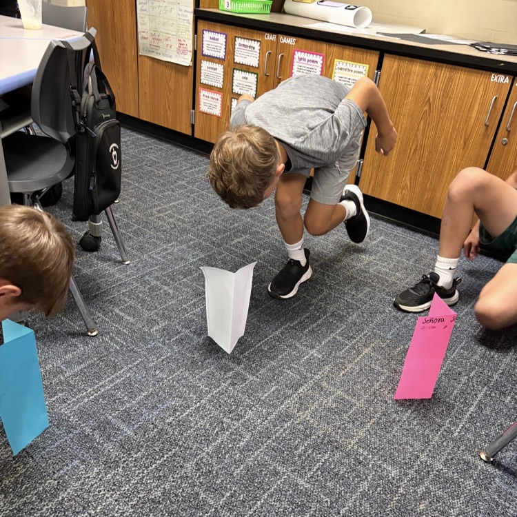 6th graders attempting to pick up a paper.