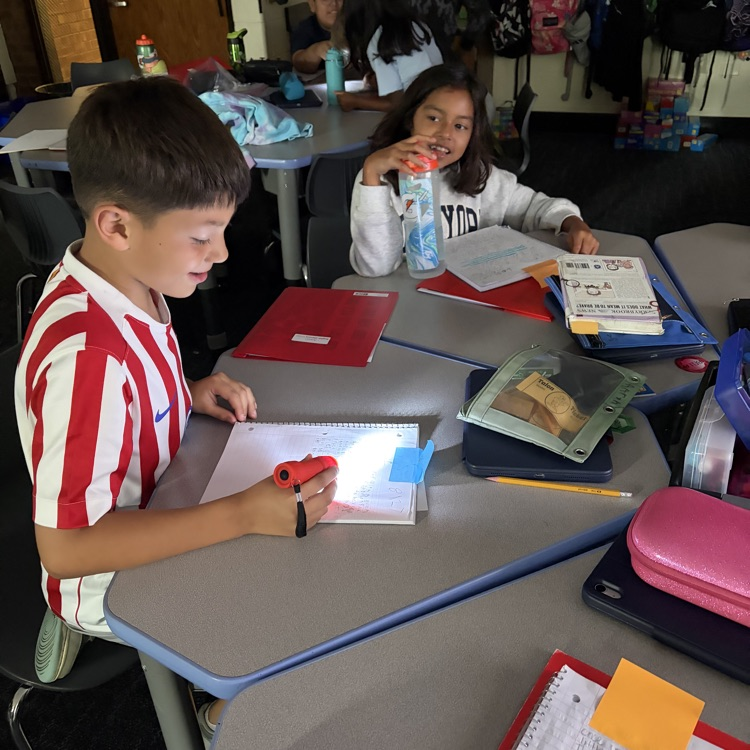 Students enjoying reading and writing in the dark with a flash light. 