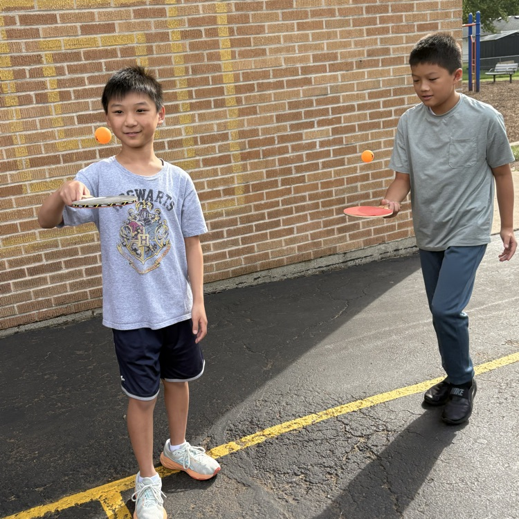 two boys boxing their ping pong ball on their paddle