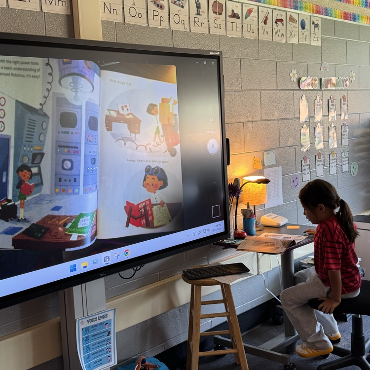Anelia reading a book in front of her class